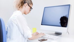 パソコンの姿勢を調整してテレワークの頭痛に対処する女性